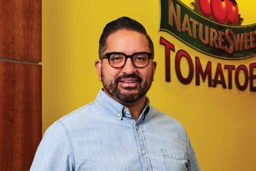 Sergio Trujillo standing in front of sign for "Nature Sweet Tomatoes"