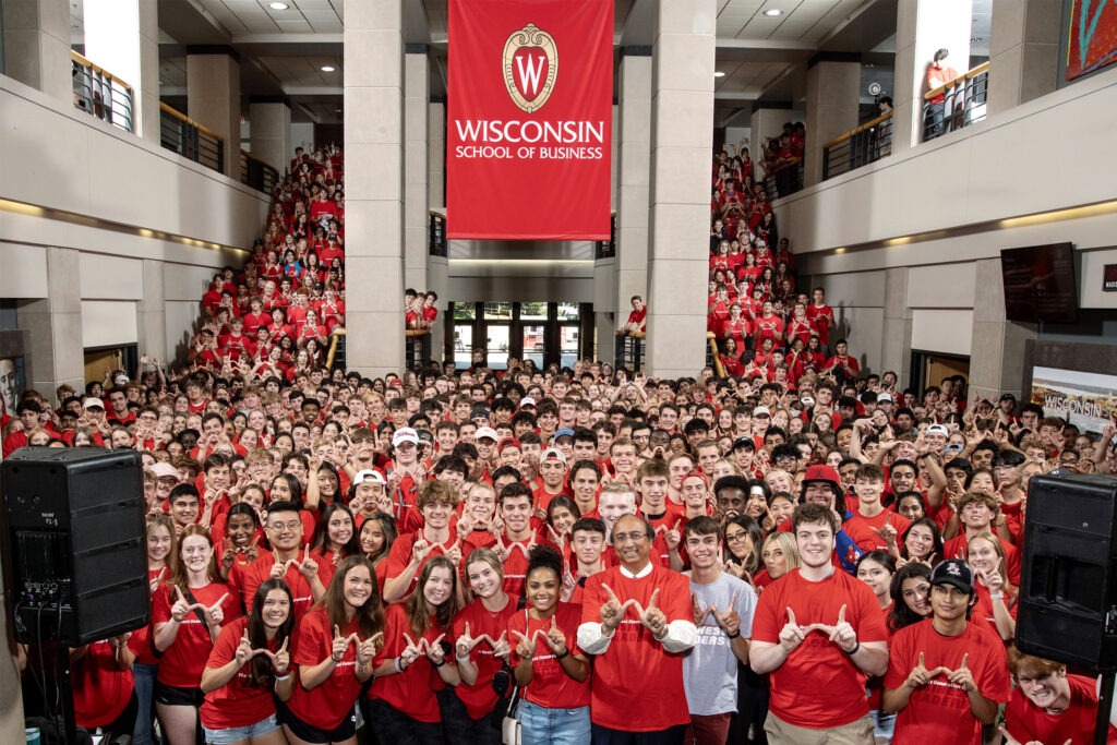 Hundreds of new WSB students wearing red t-shirts gather with Dean Vallabh Sambamurthy for a welcome event in Grainger Hall.