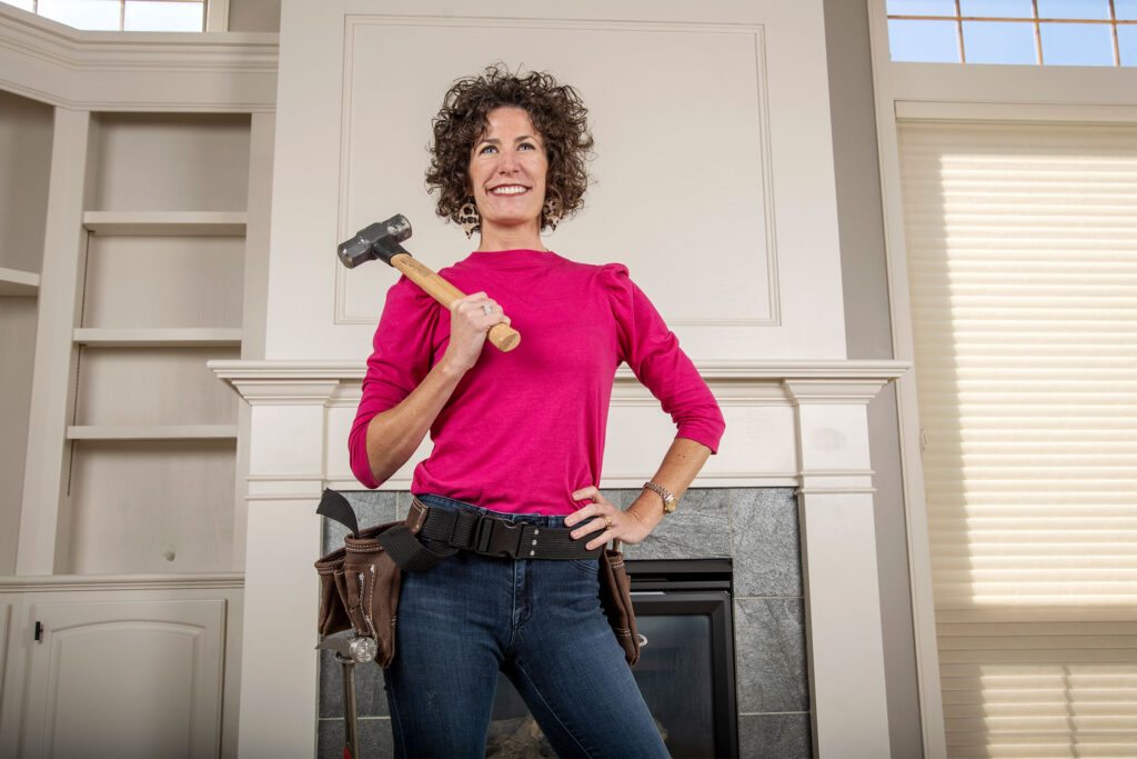 WSB alumna Lindsey Uselding stands with a hammer in a house that her family business is helping restore.