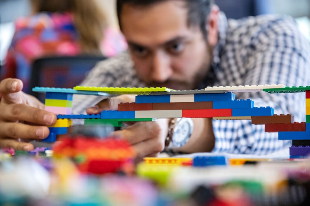 A professional MBA student builds a structure from Legos.