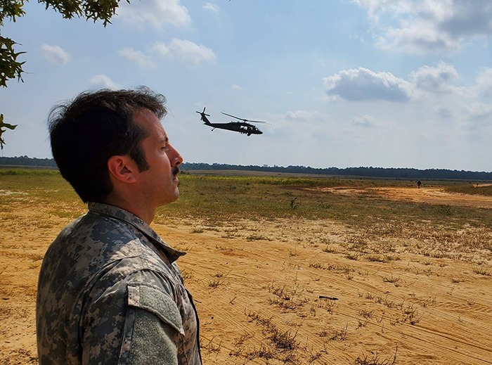 James standing in a field with a helicopter landing nearby