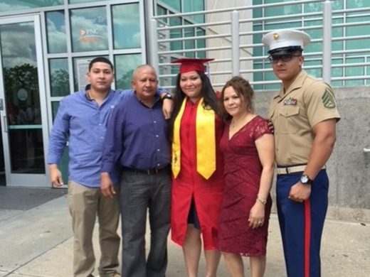 Avi, wearing graduation robes, with her parents and brothers