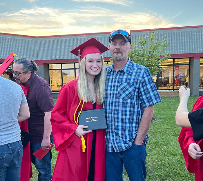 Trystyn in graduation cap and gown posing with her father