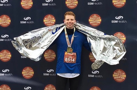 Sam posing with a shiny silver towel after completing a marathon