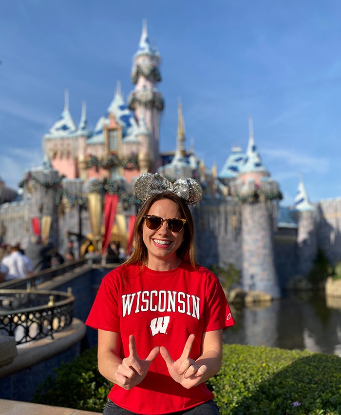 Natalie posing in Badger gear in front of Disney Castle