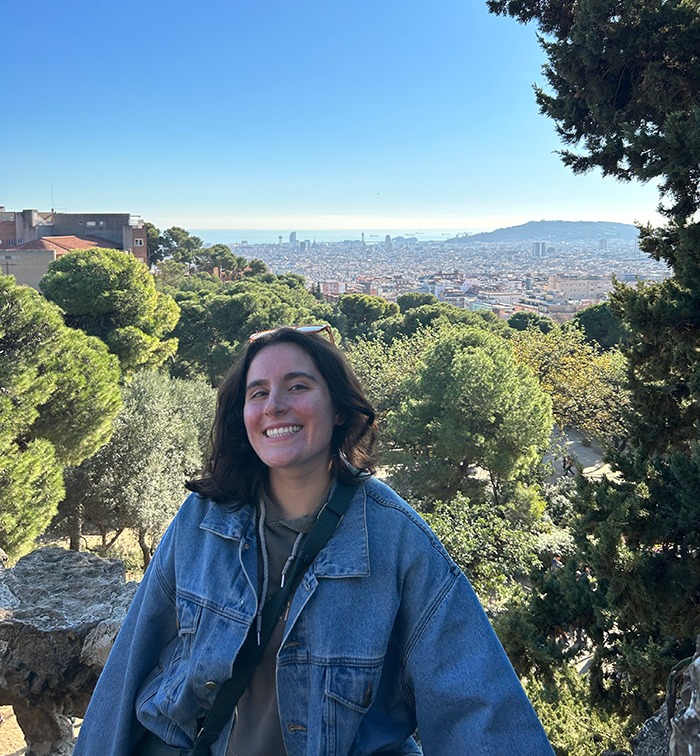 Angie with bushes around her and a city in the background