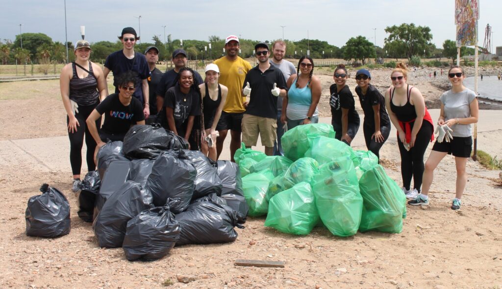 Wisconsin MBA students posing behind the multiple bags of trash they collected while cleaning a river in Buenos Aires