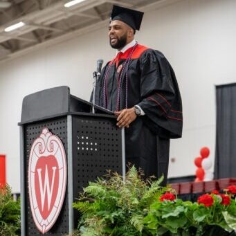 May 2022 graduate, Bryson Williams, stands at lectern and delivers student speaker speech at graduation celebration.