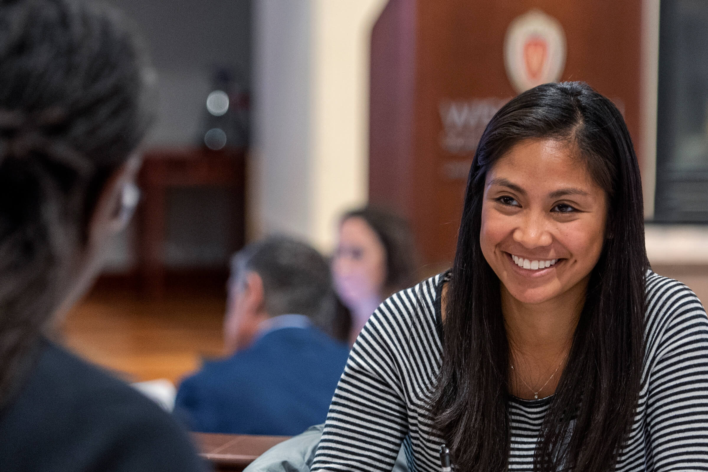 A group of people sitting at a table with a woman smiling in focus