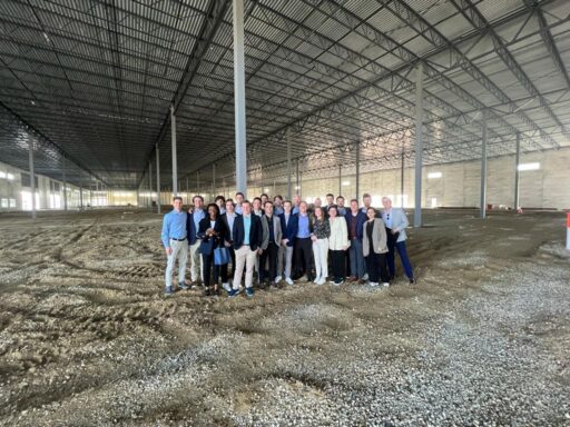 Real estate private equity students pose while touring a warehouse construction site