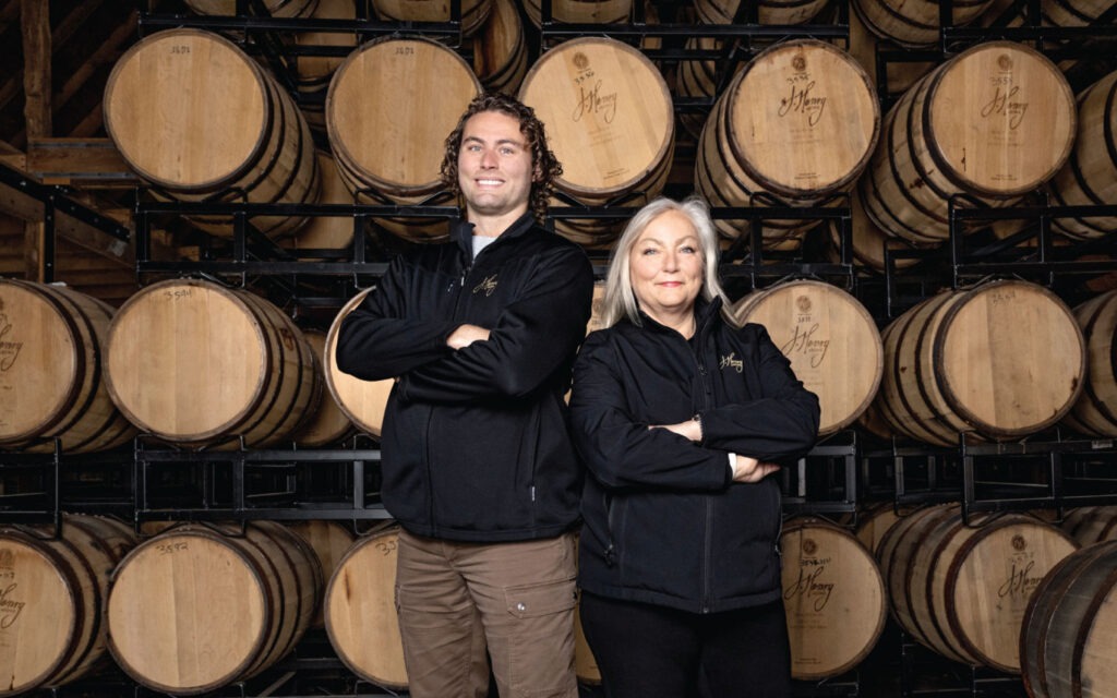 Liz and Joe Henry standing in front of barrels