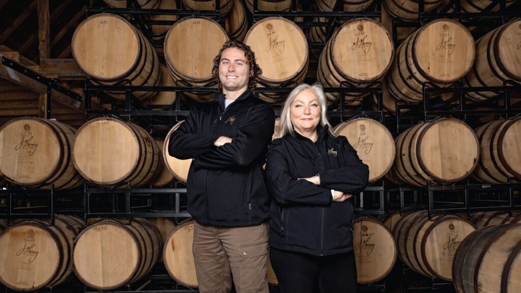 Liz and Joe Henry standing in front of barrels