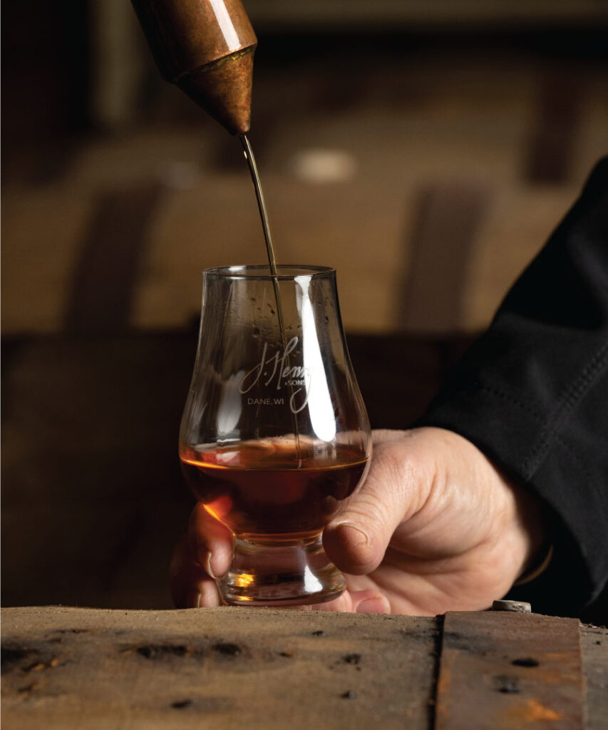 Someone holding a glass with bourbon being poured into the glass