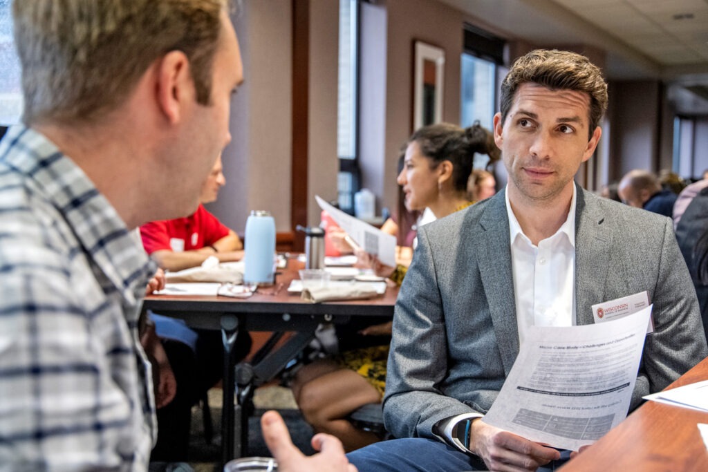 two men talking while seated at a table