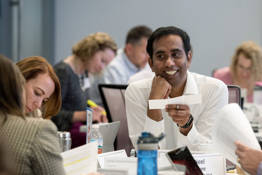 A man smiling as he reads a piece of paper