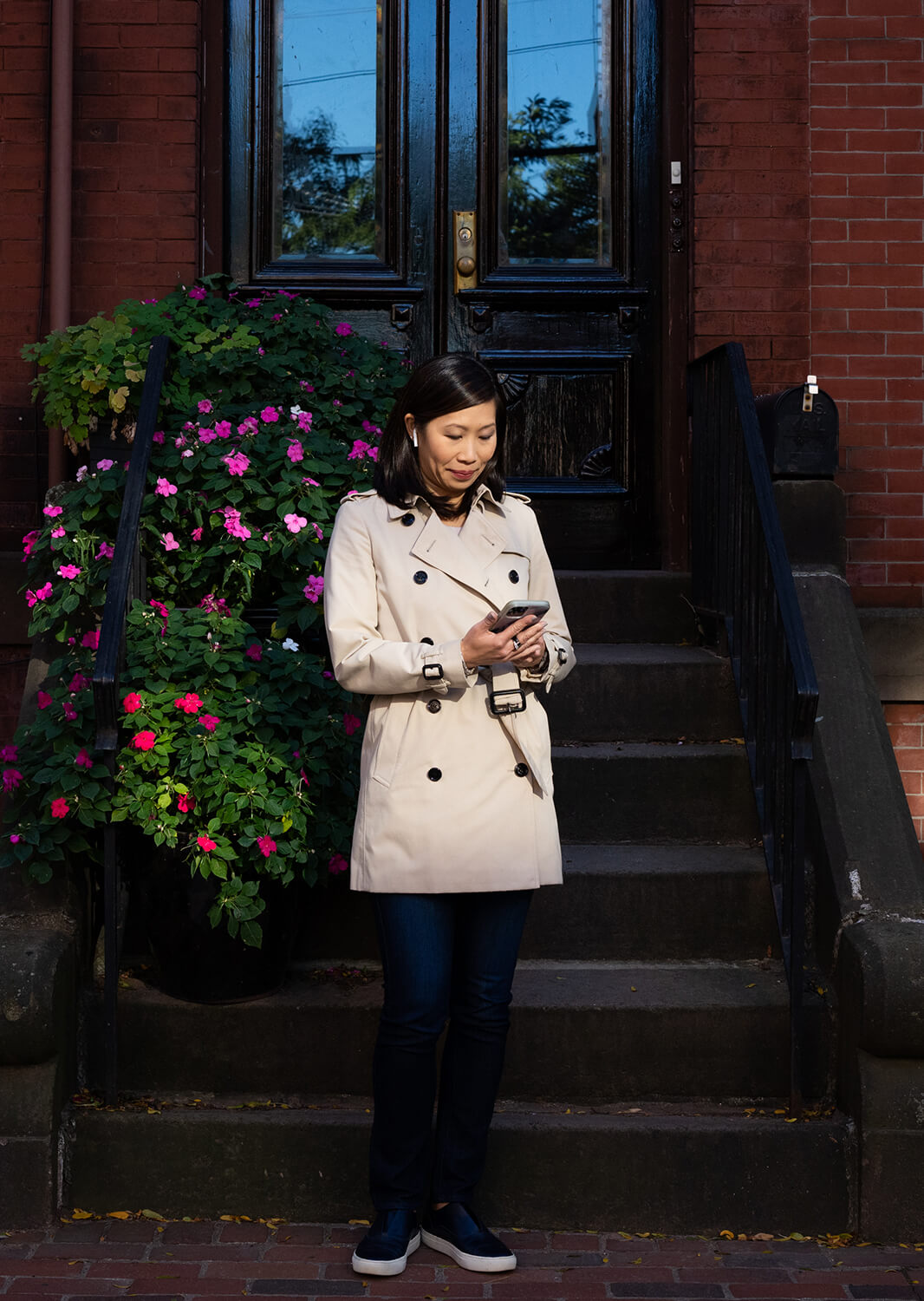 Cynthia standing in front of stairs looking at her phone