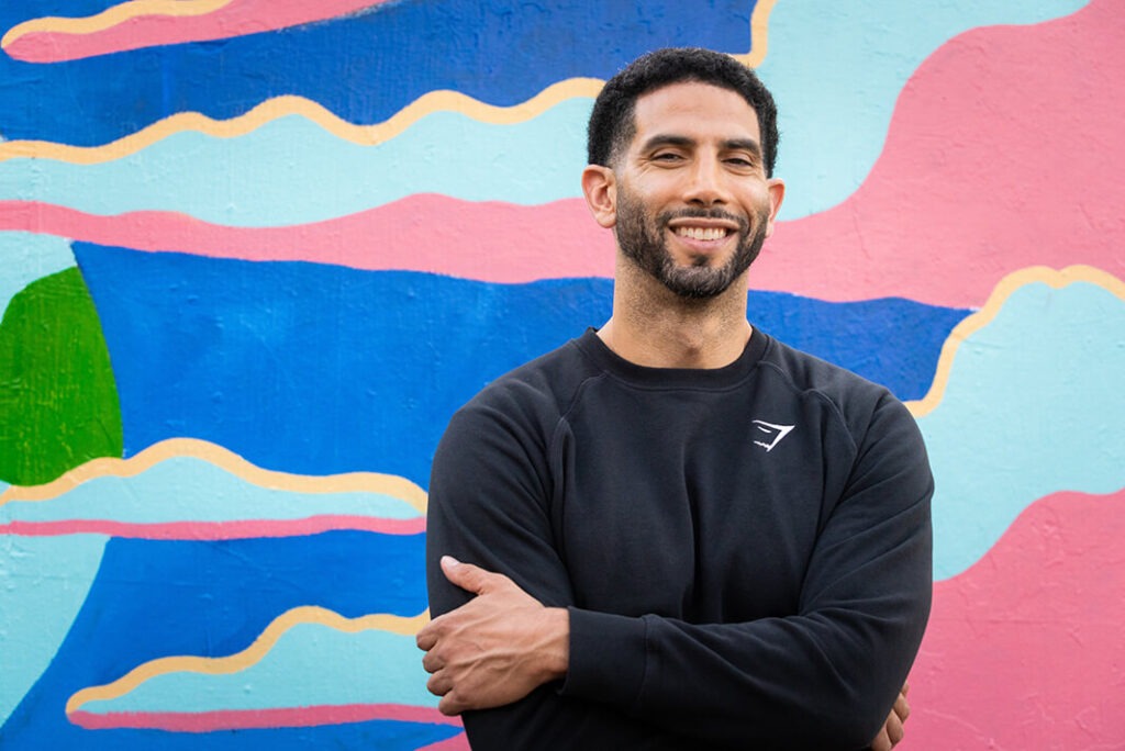 Sennai smiling in front of a colorful mural