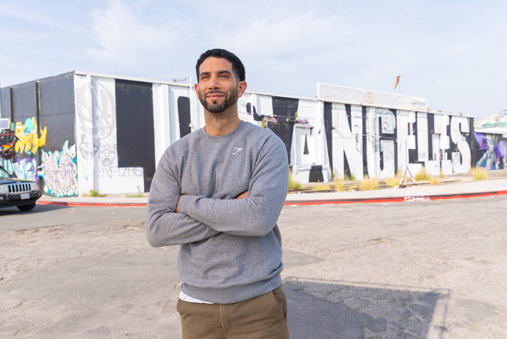Sennai standing in front of a building with "Los Angeles" written over the side