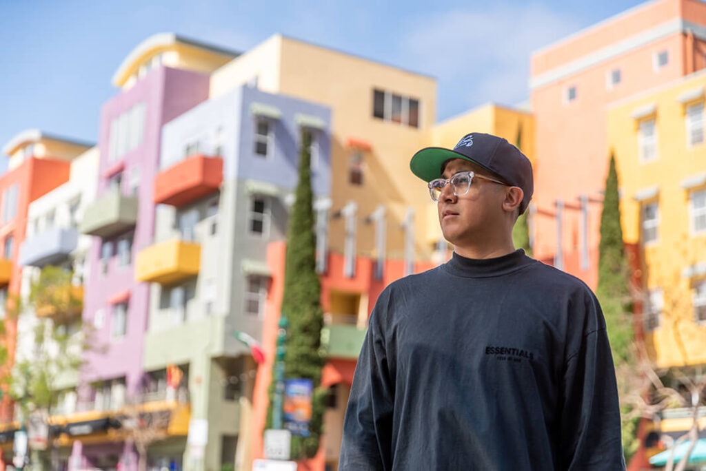 Noe standing with colorful buildings behind him
