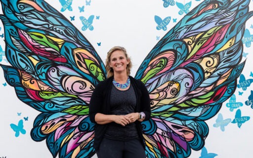 Johnson standing in front of painted butterfly wings on mural