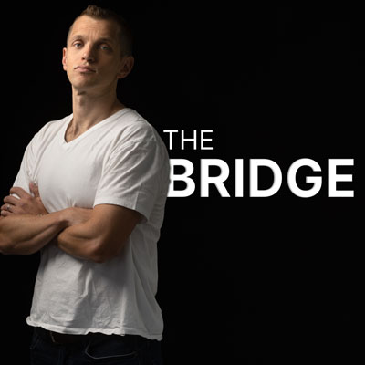 Vandehey posing in front of logo for his podcast, The Bridge
