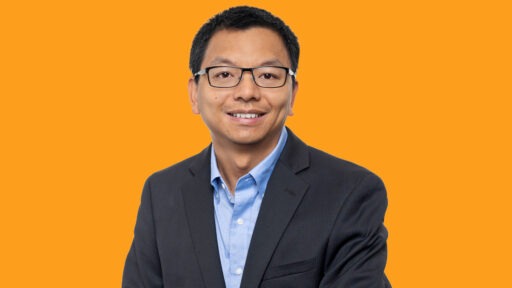 Allen Li smiling in front of orange background