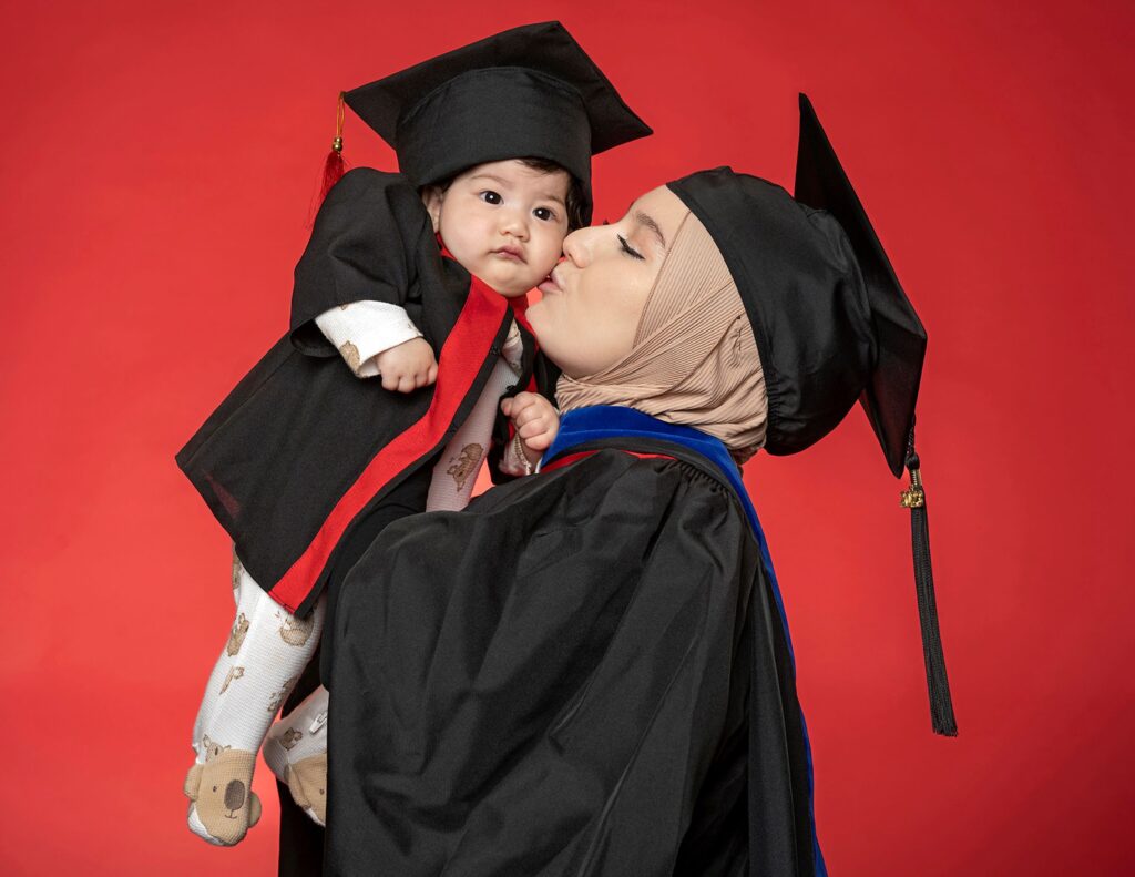 Muslimabonu Juraeva gives her baby a kiss while wearing graduation regalia