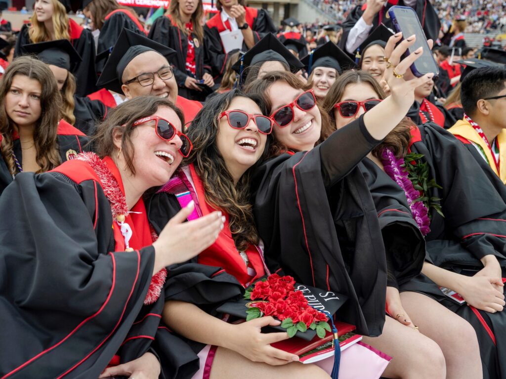Graduates wearing red sunglasses celebrate with a picture at Camp Randall