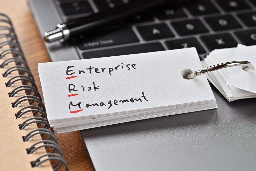 words "Enterprise Risk Management" on paper, resting on a laptop keyboard