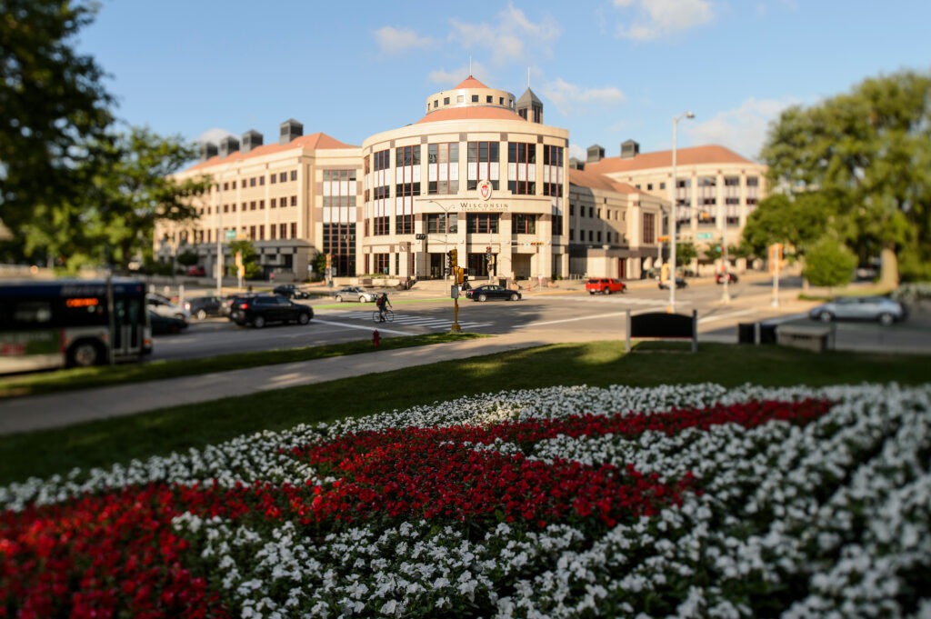 Grainger Hall behind red and white flowers creating a "W"