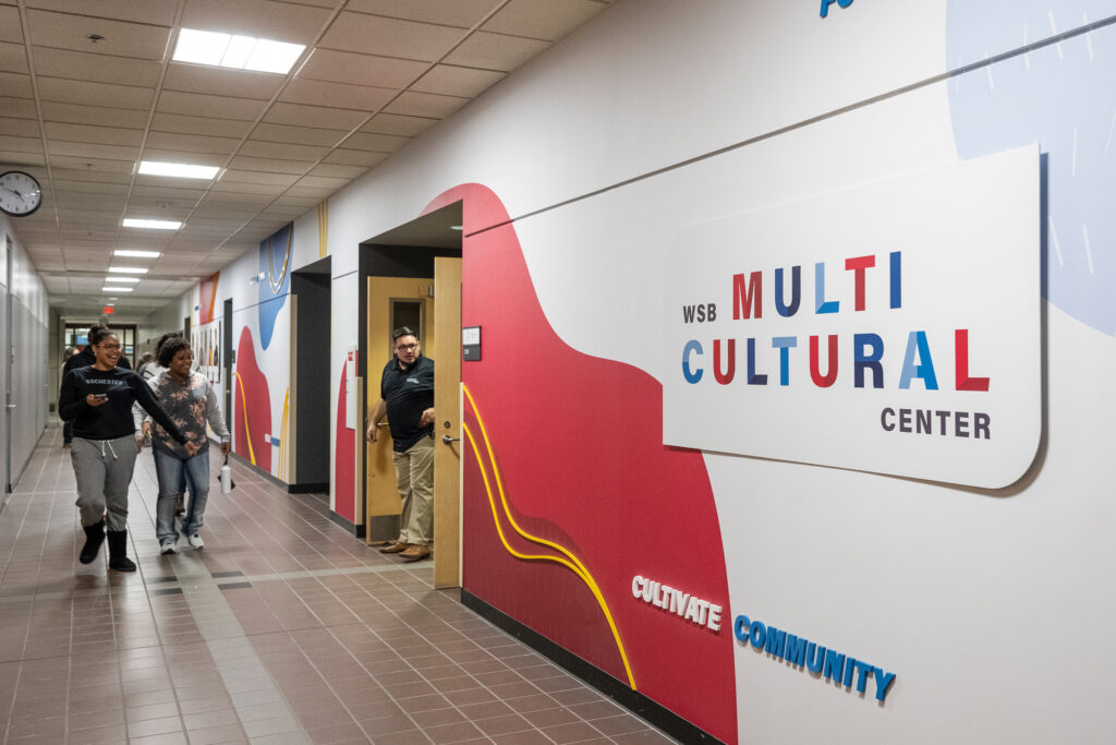 People walk down the hallway next to the sign for the Multicultural Center
