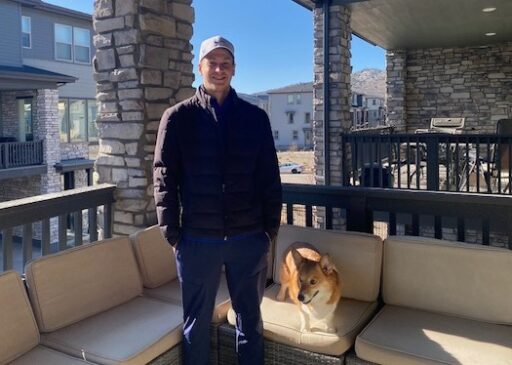 Ryan Thielen standing on an outdoor balcony with his dog, Toby