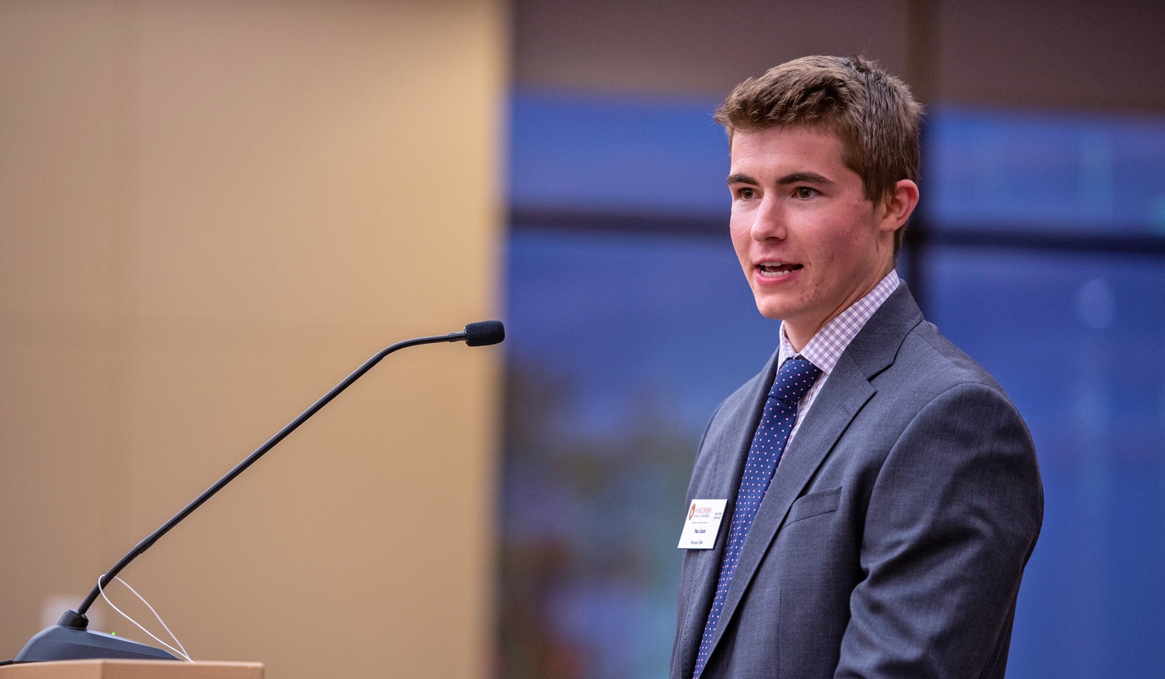 A student gives a presentation with a lectern and microphone in front of him