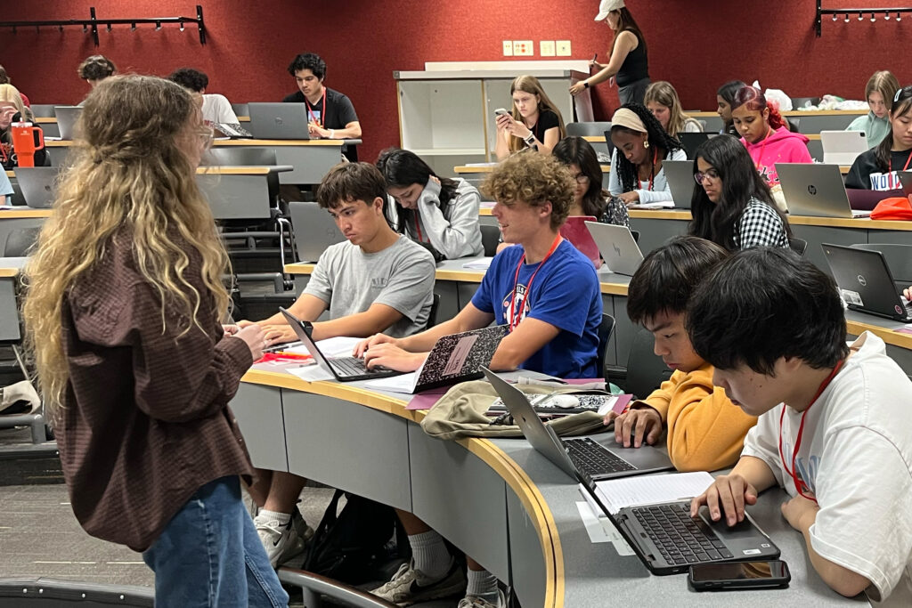 A woman standing in front of a group of sitting students in a classroom