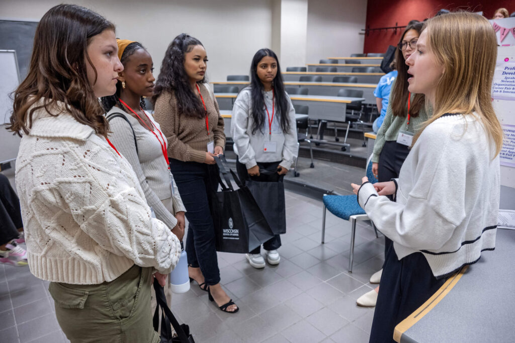 Six women standing in a classroom talking.