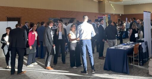 Many students and industry representatives are standing in conversation at the career fair.