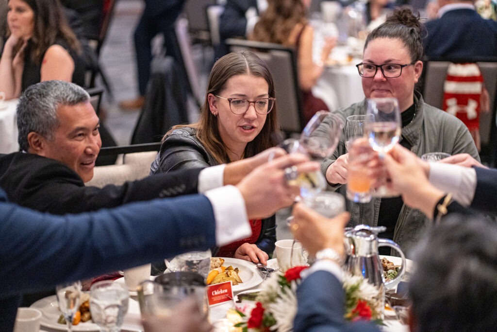 Wisconsin Business Alumni Board members Emil Ray Sanchez (BBA ’88) and Katie Lorenz (BBA ’12), plus other guests, raise a toast over dinner to the 2024 recipients of WSB’s Alumni Awards.