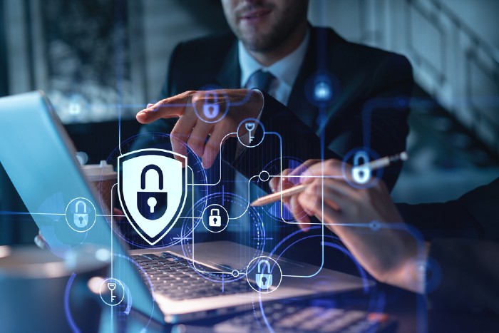 Two colleagues working in front of an open laptop. Images of locks and keys appear in front of the photo.