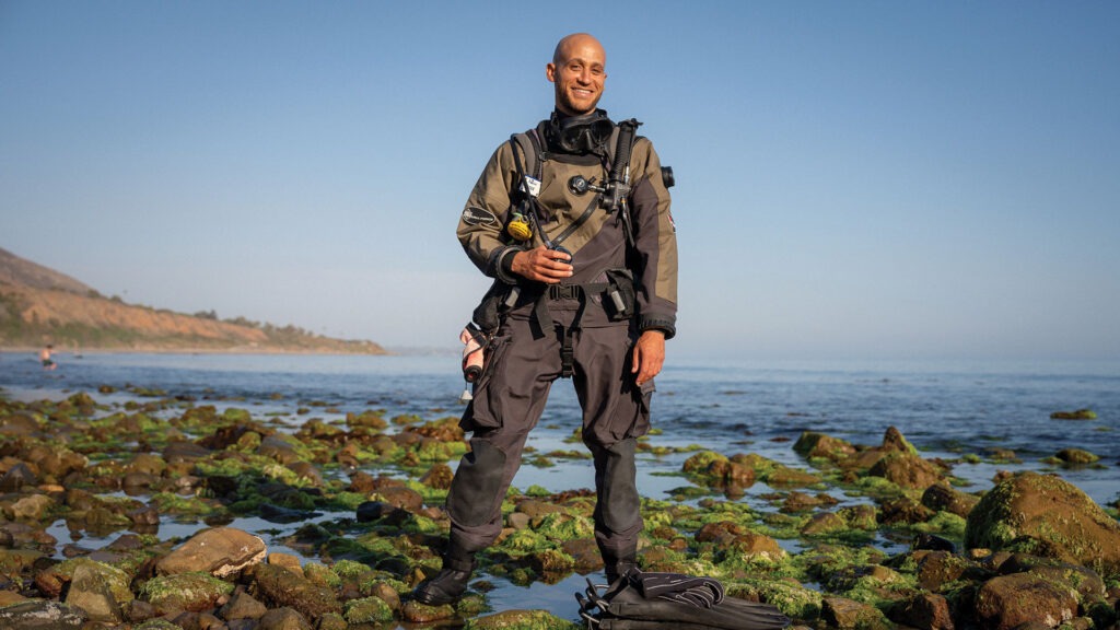 Maxwell Bracey wearing a scuba outfit standing by a large body of water