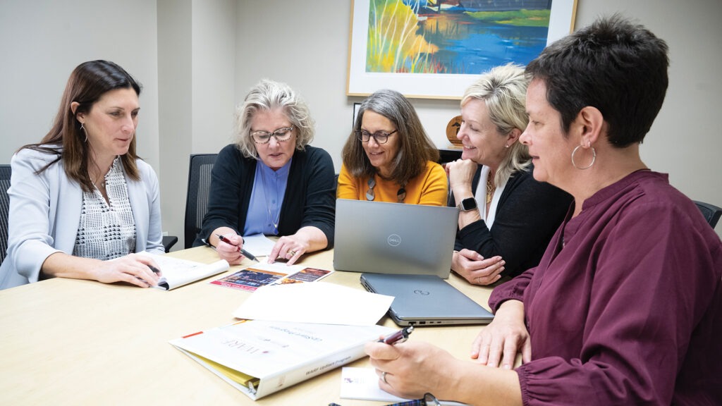 Amy Bruner Zimmerman, Chris Gruneberg, Michelle Somes-Booher, Anne Inman, and Stephanie Achten sitting at a table looking at a paper