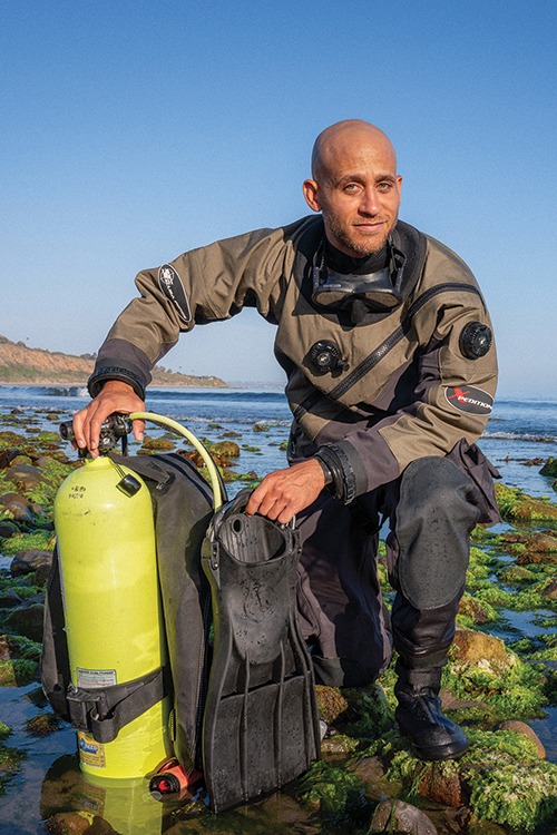 Maxwell Bracey wearing a scuba outfit standing by a large body of water