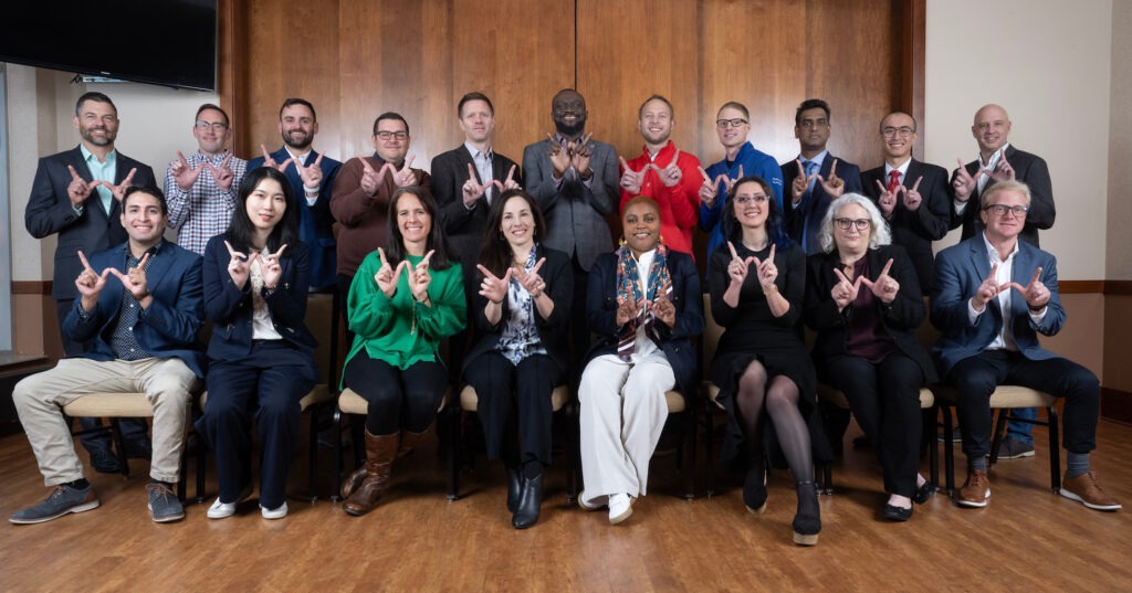 Alumni group smiling holding a W sign with their hands