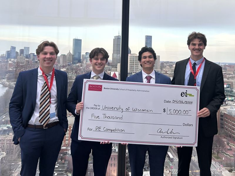 (Left to right) Alex Lortscher, Ethan Gomez, Nikhil Robinson, and Grant Atkinson holding their first place check with the Boston City in the background.