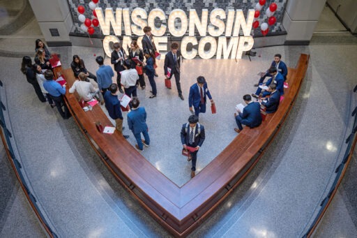 students mingle in front of the case competition sign in lights at the waterwall