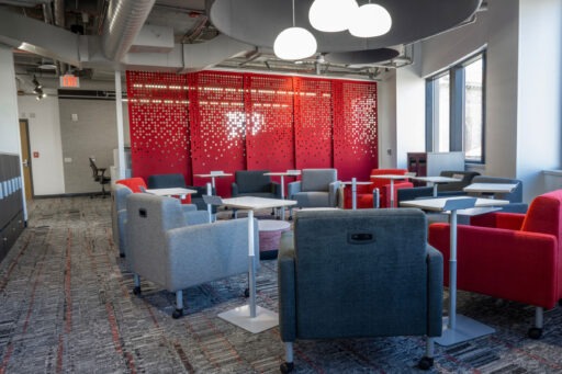 A new suite on the Northwest wing of the 5th floor features flexible seating options for easier collaboration. Pictured is a space with movable wall panels and a group of upholstered chairs on wheels with portable tables.