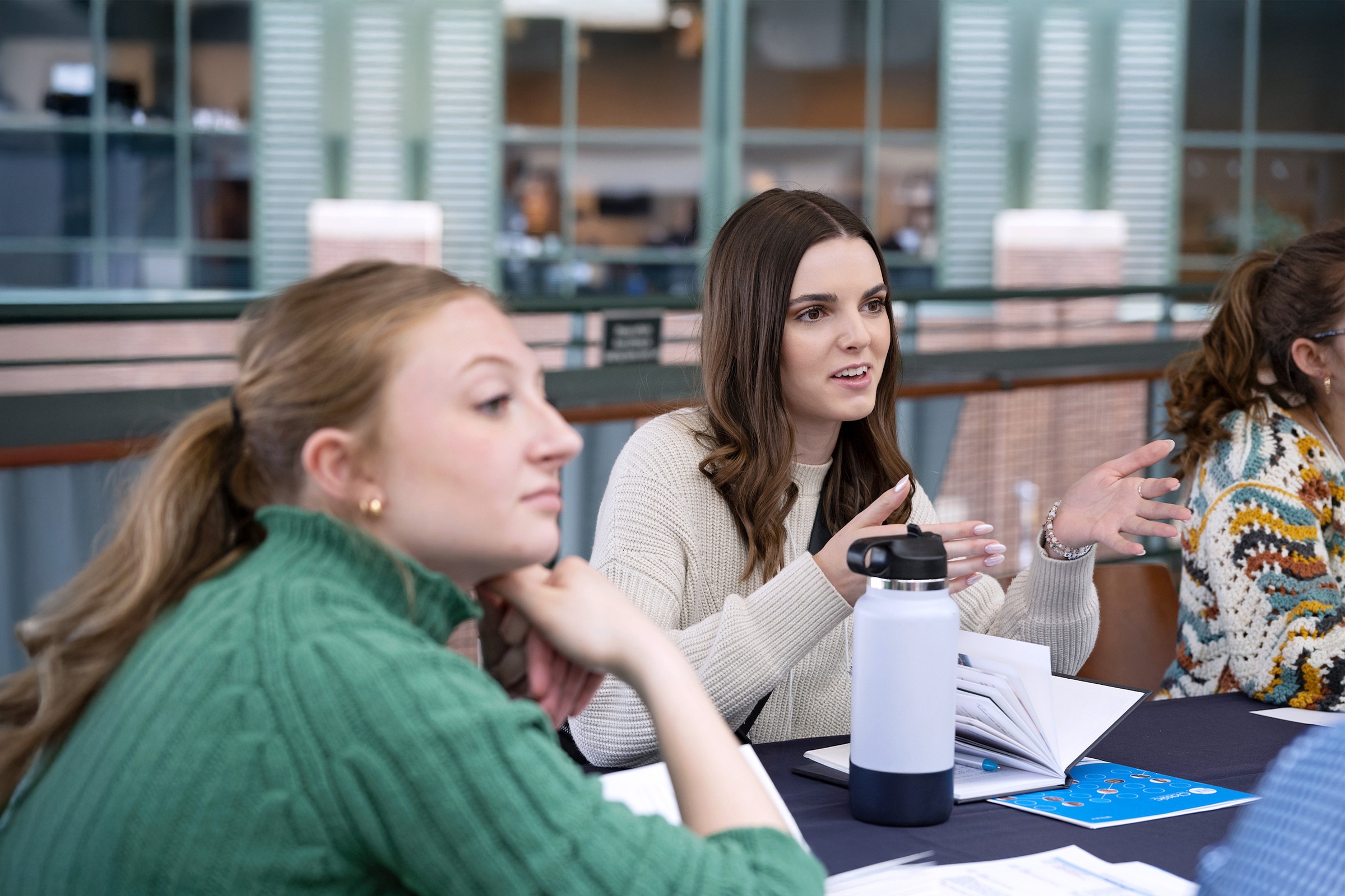 A group of women sitting at a table with notebooks in front of them