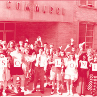 Students stand in front of the old Commerce Building, holding a sign saying "So long".