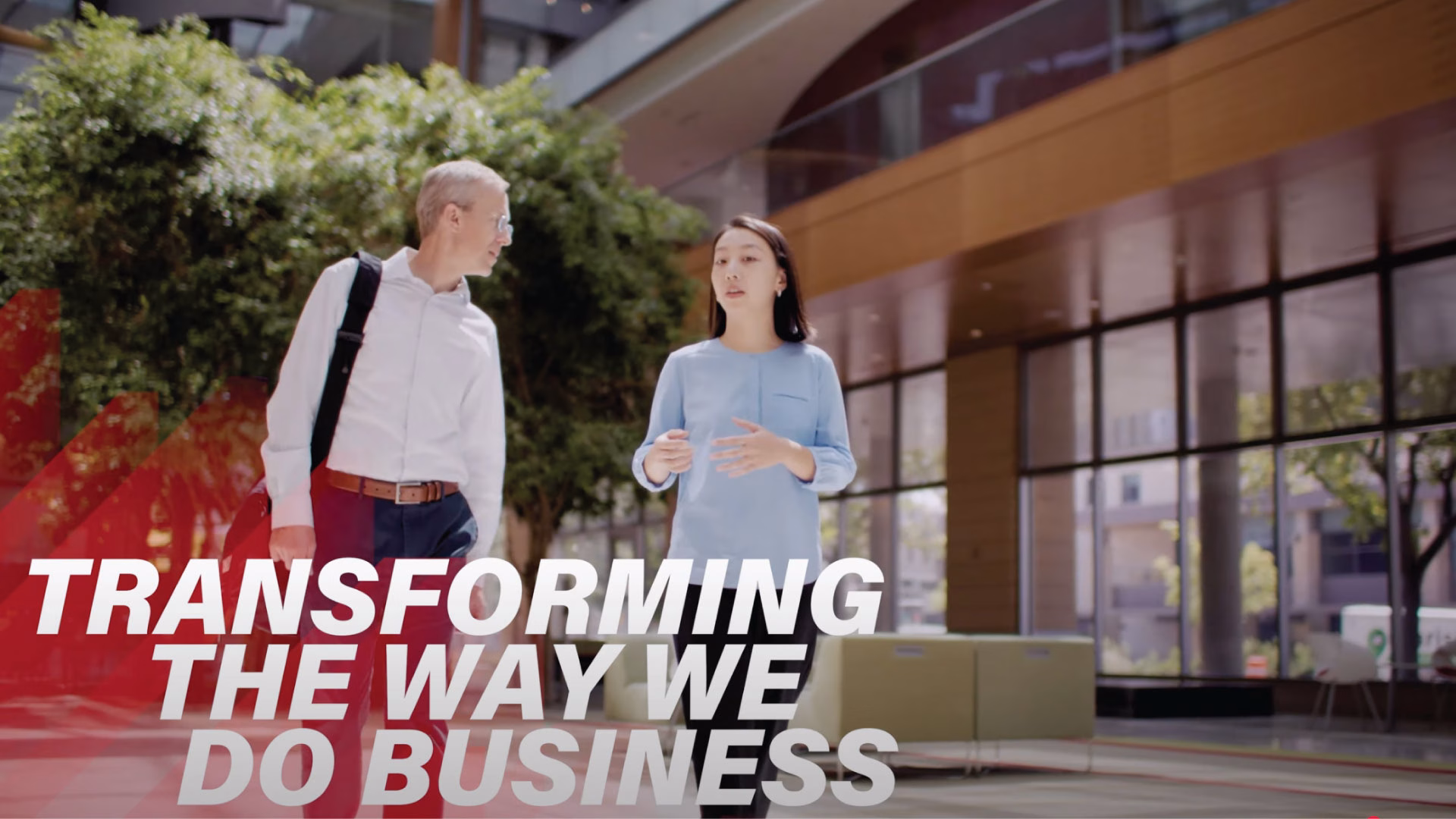 Two people are walking and talking inside a building.