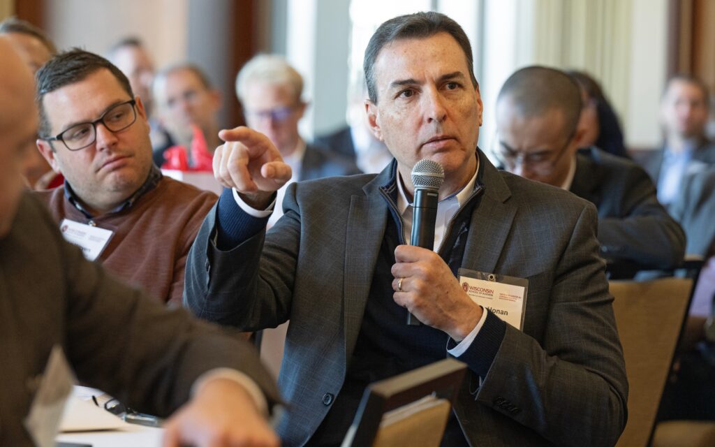 A board member sits in a chair and speaks into a microphone.