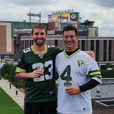 David Balistreri poses with his son, both wearing Packers football jerseys.